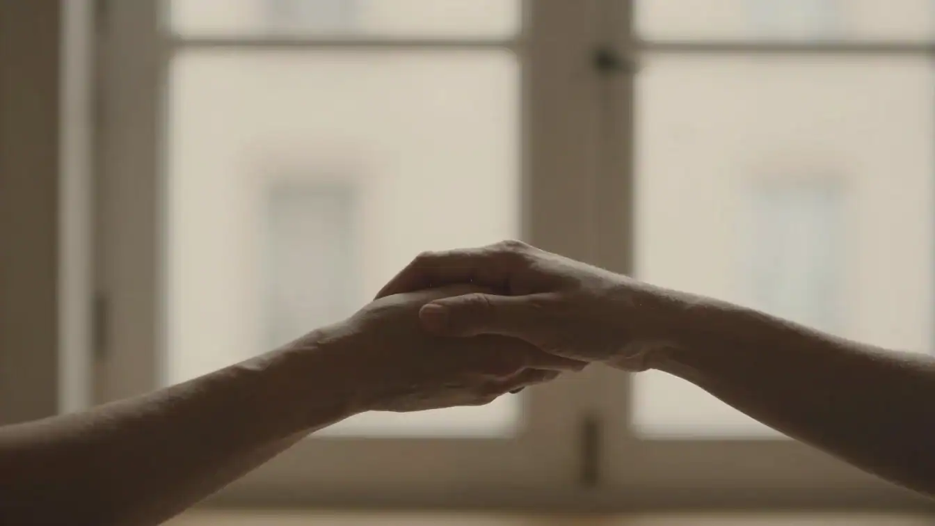 Two hands gently clasped, representing connection, in a warm, mut